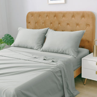 A bed with gray bedding and a tufted brown headboard in a bedroom setting.