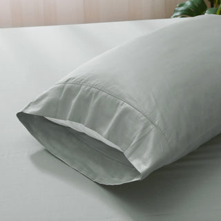 Light gray pillow on a bed with a neutral background