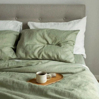 Bed with green bedding and a cup of coffee on a wooden tray