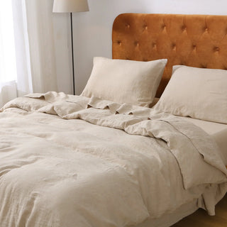 Beige bedding on a bed with a brown headboard in a bedroom setting.