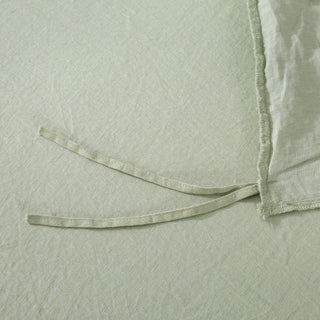 Close-up of a textured green fabric with a ribbon on a matching background