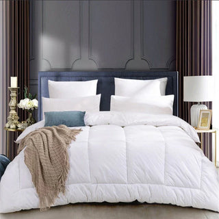 White comforter set on a bed with decorative pillows and a dark headboard.