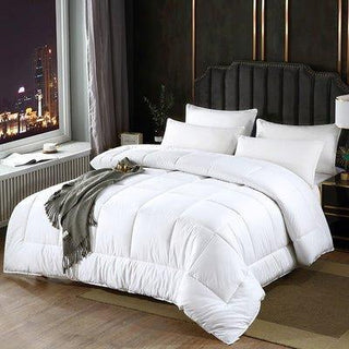 White comforter on a bed in a bedroom with a cityscape view.