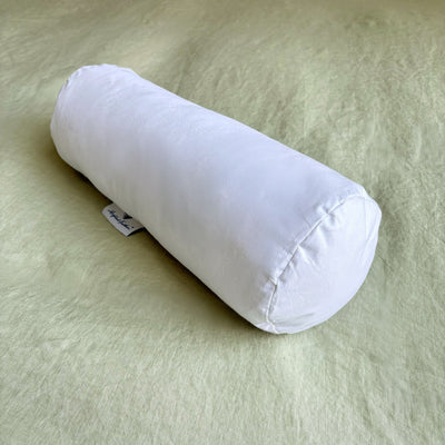 White cylindrical pillow on a light green bedspread