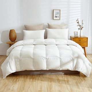 White comforter on a bed in a bedroom setting with wooden nightstands and decor.