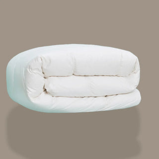 Folded white comforter on a beige background