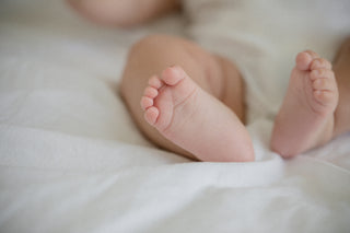 little baby feet on a white bed sheet