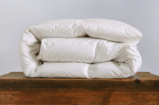 a folded fluffy duvet on a bench