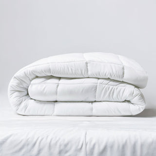 Folded white comforter on a light gray background