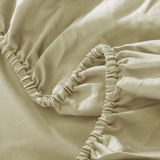 Close-up of beige fitted sheet with elastic waistband on a bed.
