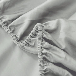 Close-up of a fitted sheet with elastic band on a bed.