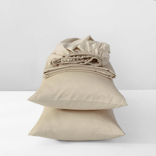 Stack of beige folded bed sheets on a white background