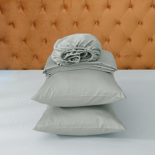 Stack of gray bedding on a bed with a tufted headboard.
