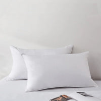 Two white pillows on a bed with a neutral background