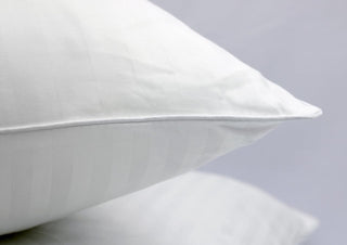 Close-up of white cotton pillows with pillow protector on sheets.