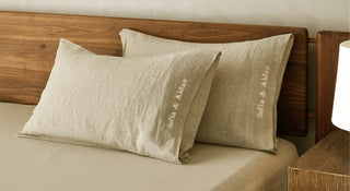 Beige pillows with 'sofia & Aidan' embroidery on a wooden bed.