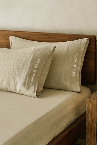 Beige pillows with 'sofia & Aidan' embroidery on a wooden bed.